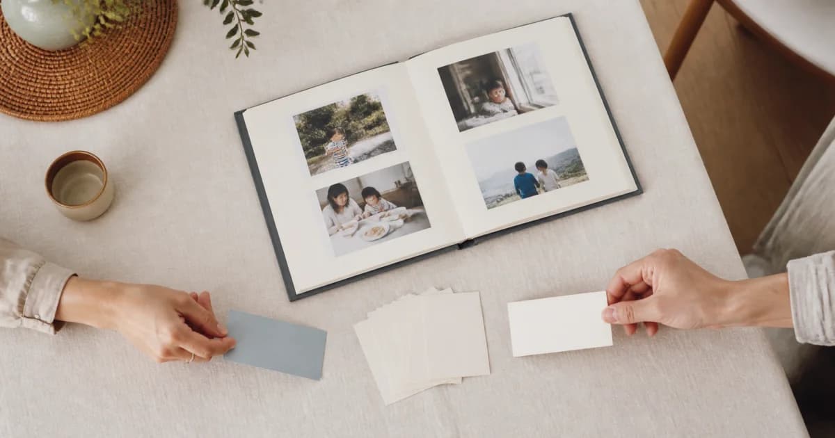 Two people holding blank cards of different colors beside an open family photo album